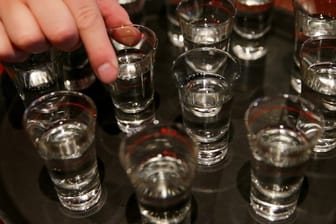 Eine Hand greift nach einem der gefüllten Schnapsgläser (Symbolbild): 7,9 Millionen Deutsche konsumieren laut Suchtbericht Alkohol "in gesundheitlich riskanter Weise".