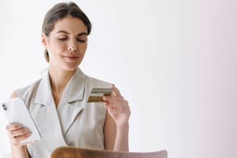 Frau mit Kreditkarte (Symbolbild): Die Kreditkartenprüfnummer wird beim Onlinezahlen wichtig.