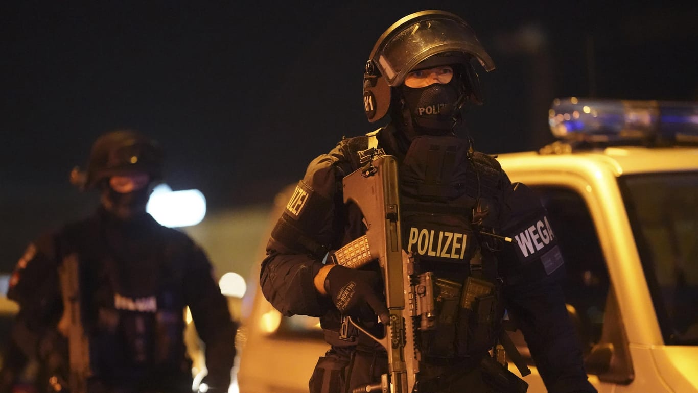 Schwer bewaffnete Polizisten gehen am Schwedenplatz an einem Polizeifahrzeug vorbei: Bei einem mutmaßlichen Terroranschlag in der Wiener Innenstadt sind am Montagabend mehrere Menschen getötet und verletzt worden.