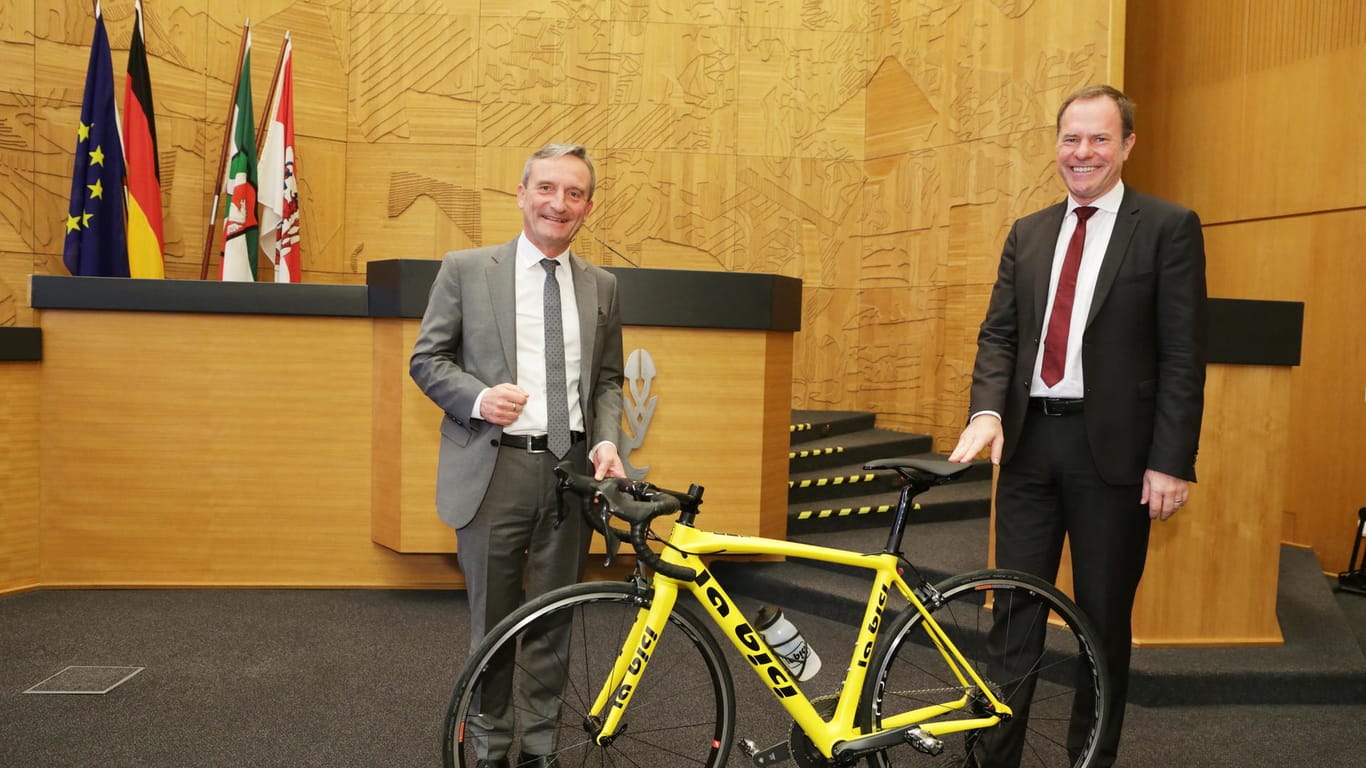 Oberbürgermeister Dr. Stephan Keller (r.) übergab seinem Amtsvorgänger Thomas Geisel bei der Verabschiedung im Plenarsaal ein Rennrad.