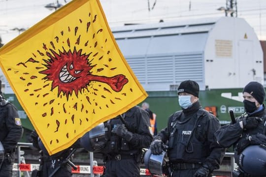 Mit einer Coronavirus-Karikatur auf einer Fahne protestieren Anti-Atomkraft-Gegner in Biblis gegen den Castor-Transport.