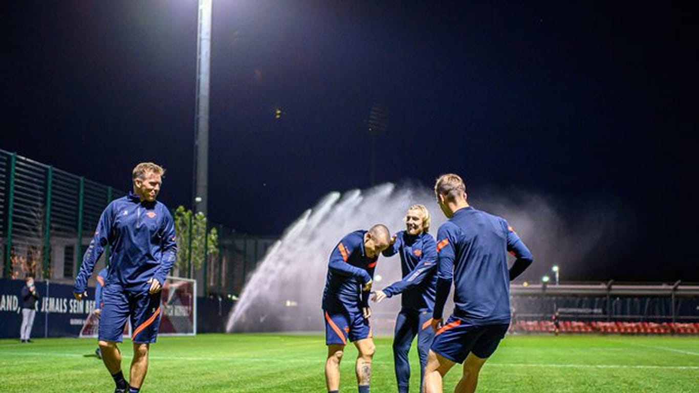 Leipzigs Trainer Julian Nagelsmann (l) schaut seinen Spielern beim Aufwärmen zu.