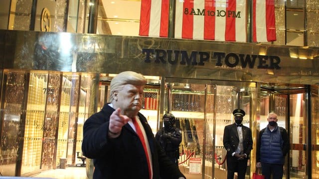 Ein Mann mit einer Trump-Maske in der Hand gestikuliert vor dem Trump Tower, der von einem Polizisten einer Spezialeinheit des NYPD auf der 5th Avenue in Manhattan am Vorabend der Präsidentschaftswahlen gesichert wird. Ein Mann mit einer Trump-Maske in der Hand gestikuliert vor dem Trump Tower, der von einem Polizisten einer Spezialeinheit des NYPD auf der 5th Avenue in Manhattan am Vorabend der Präsidentschaftswahlen gesichert wird.