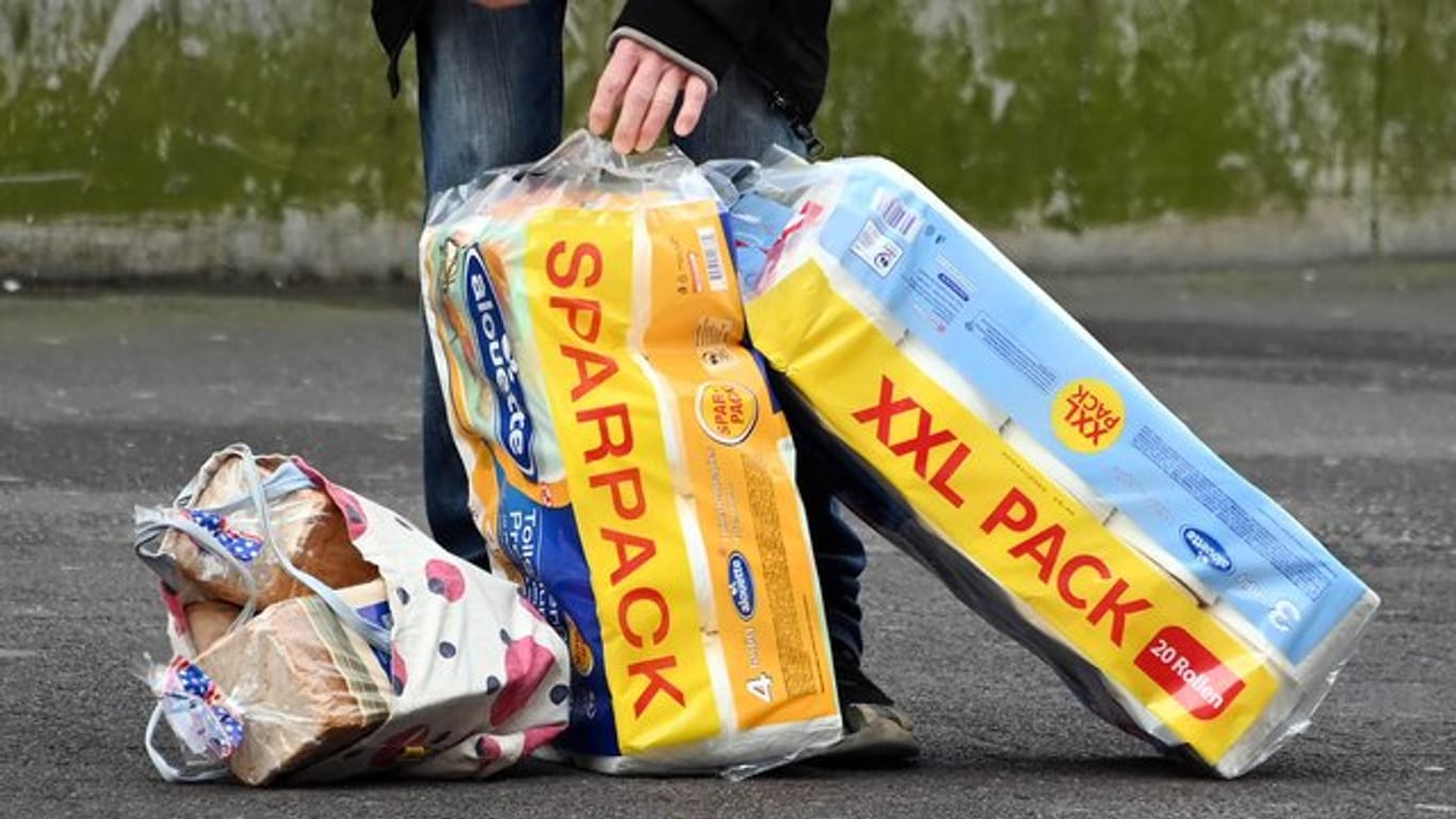 Eine Person steht mit zwei XXL-Packungen Toilettenpapier an einer Straße (Symbolbild): Hamburger Supermärkte gehen gegen Hamsterkäufe vor.