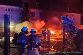 Feuerwehrkräfte stehen vor brennenden Autos: In Berlin-Tegel hat es auf einem Gelände der Bundespolizei gebrannt.