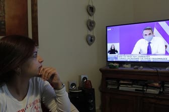 Eine Frau verfolgt die TV-Ansprache von Griechenlands Premierminister Mitsotakis.