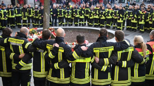 Am Königsplatz in Augsburg trauern Feuerwehrmänner.
