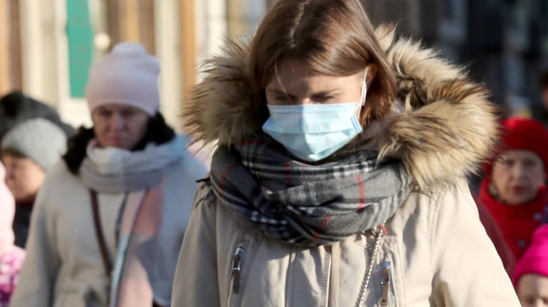 Eine Frau im Wintermantel mit Mund-Nasen-Schutz (Symbolbild): Das Coronavirus kann sich in den kühleren Monaten wahrscheinlich leichter verbreiten als im Sommer.