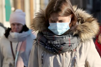 Eine Frau im Wintermantel mit Mund-Nasen-Schutz (Symbolbild): Das Coronavirus kann sich in den kühleren Monaten wahrscheinlich leichter verbreiten als im Sommer.
