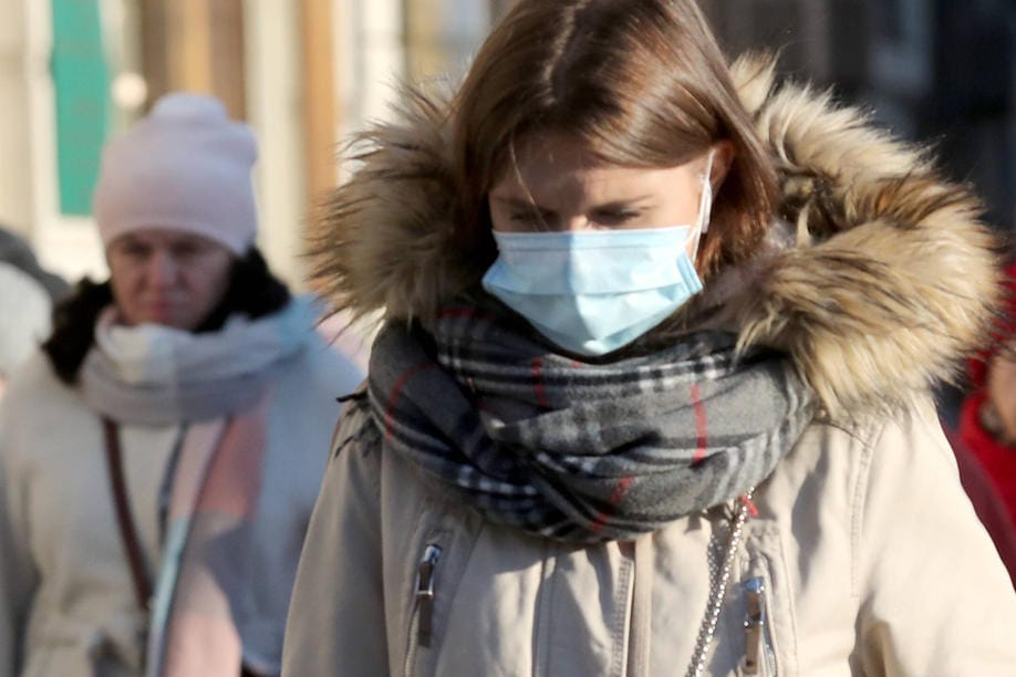 Eine Frau im Wintermantel mit Mund-Nasen-Schutz (Symbolbild): Das Coronavirus kann sich in den kühleren Monaten wahrscheinlich leichter verbreiten als im Sommer.