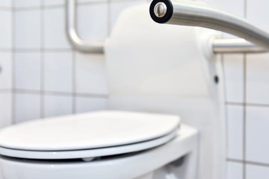 Toilette mit Griffen: Ein Griff kann älteren Menschen helfen, auch auf Toiletten mit normaler oder niedriger Sitzhöhe sicher Platz nehmen zu können.