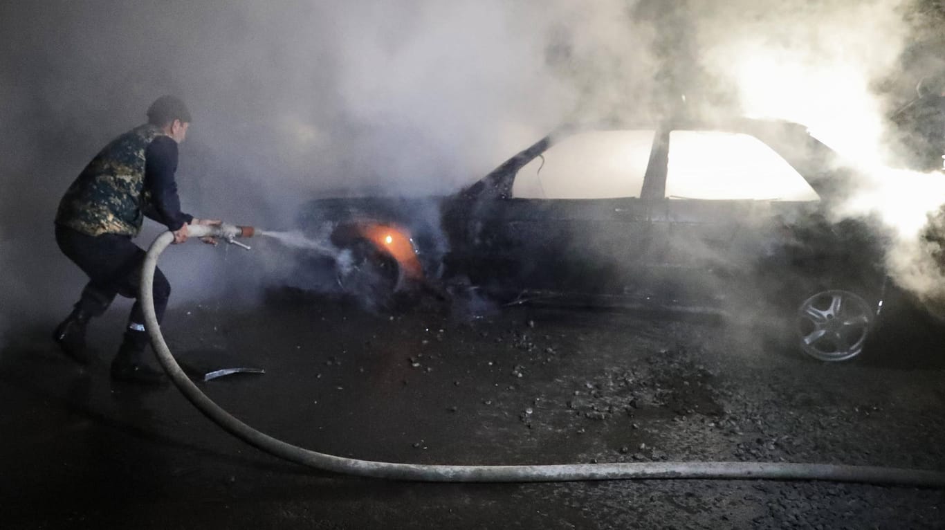 Ein Mann in Stepanakert löscht sein brennendes Auto nach einem Militärschlag.