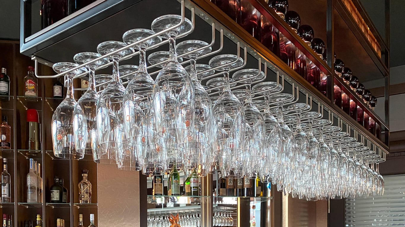 Leere Gläse hängen über einer Theke (Symbolbild): Bars, Clubs und Kneipen müssen wegen der Corona-Pandemie dicht bleiben.