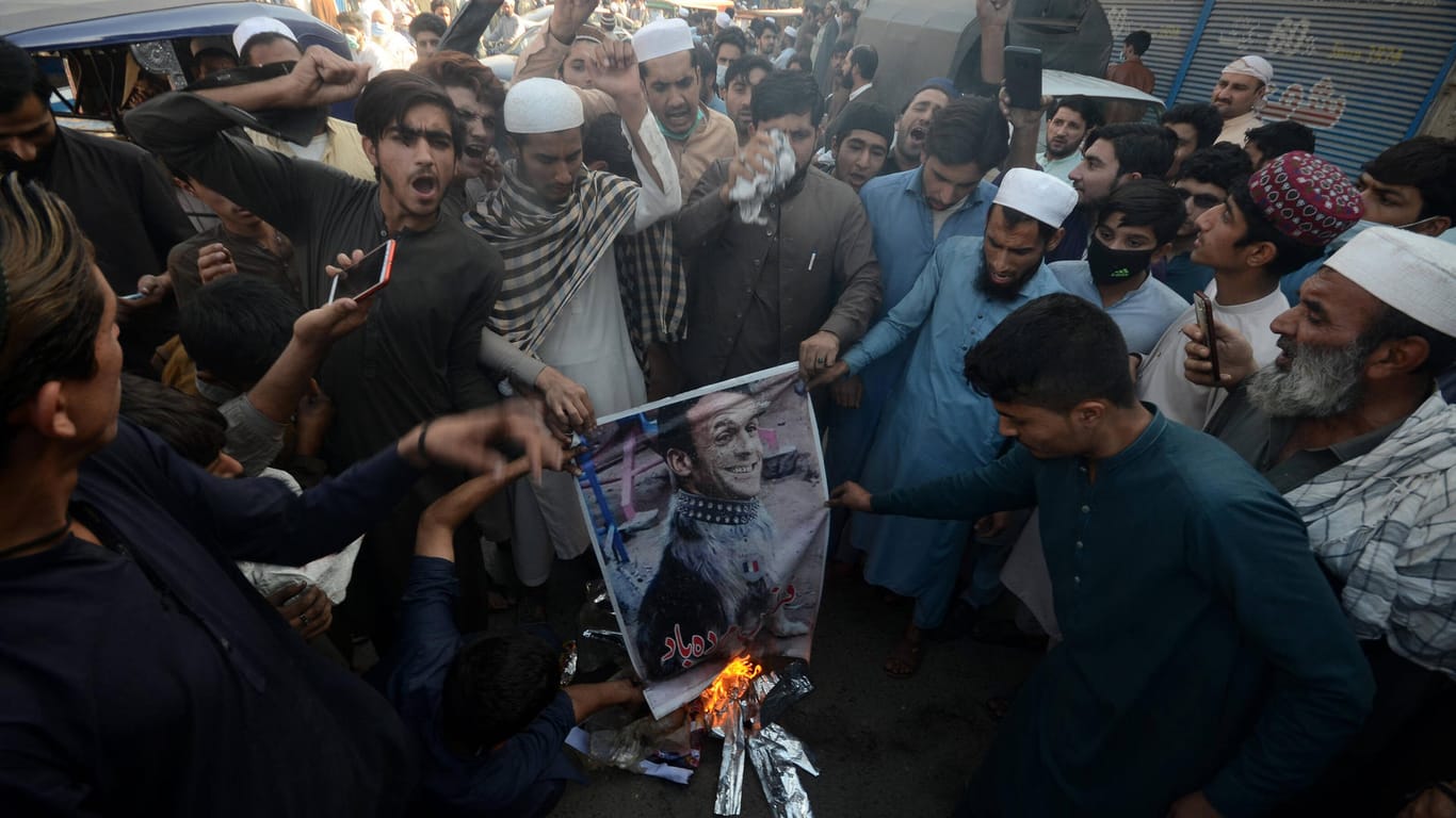 Pakistan: Menschen zünden ein Bild des französischen Präsidenten an. Sie rufen zum Boykott französischer Waren auf.
