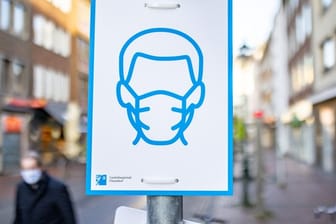 Ein Schild mit dem Symbol für Maskenpflicht an einem Straßenschild in der Innenstadt von Düsseldorf.