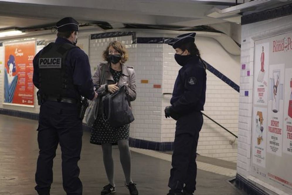 In einer U-Bahn-Station in Paris kontrollieren zwei Polizisten eine Pendlerin.
