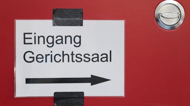 In einem Justizgebäude weist ein Schild den Weg zum Gerichtssaal.