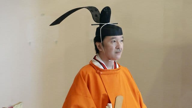 Kronprinz Fumihito von Japan steht in einer orangefarbenen Robe im Kaiserpalast bei seiner offiziellen Ernennung. Kronprinz Fumihito von Japan steht in einer orangefarbenen Robe im Kaiserpalast bei seiner offiziellen Ernennung.