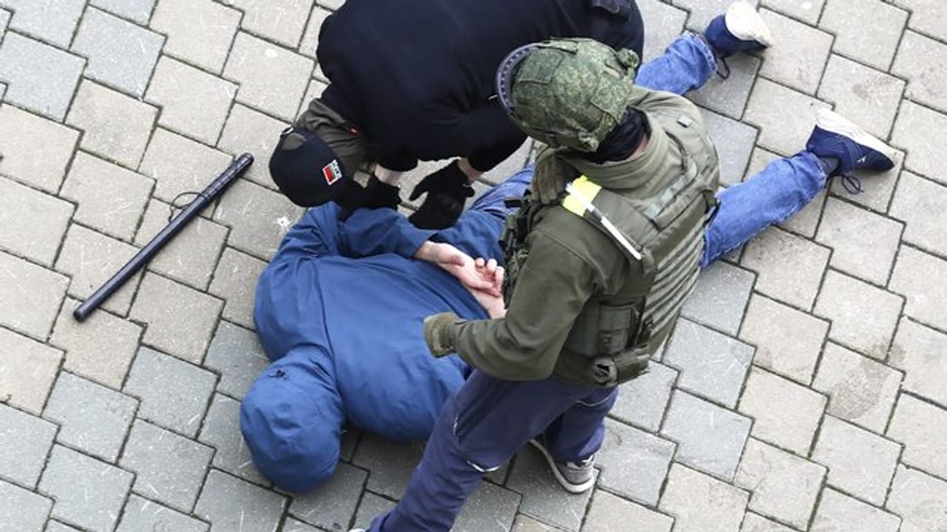Polizisten nehmen einen am Boden liegenden Mann in Minsk fest.