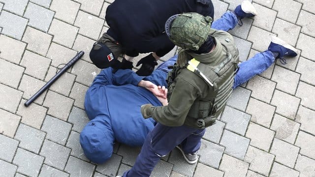 Polizisten nehmen einen am Boden liegenden Mann in Minsk fest.