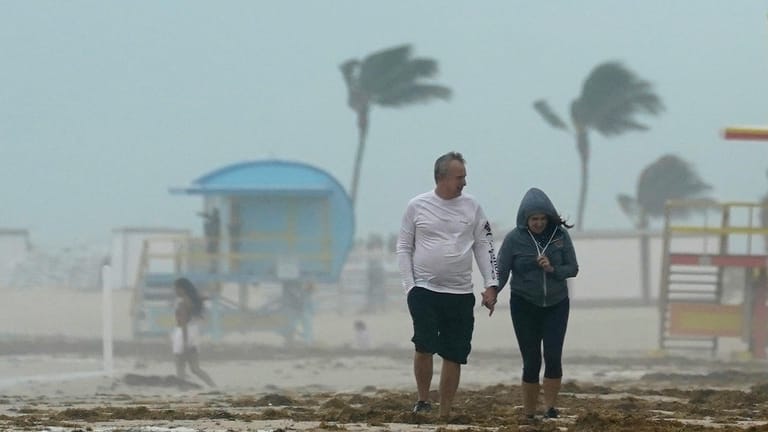 Miami Beach, USA: Ein Paar spaziert während des heftigen Tropensturms "Eta" am Strand entlang.