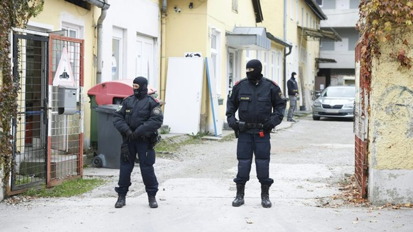 Zwei uniformierte Polizisten stehen in einer Einfahrt an einem Einsatzort der Operation "Luxor" in Graz.