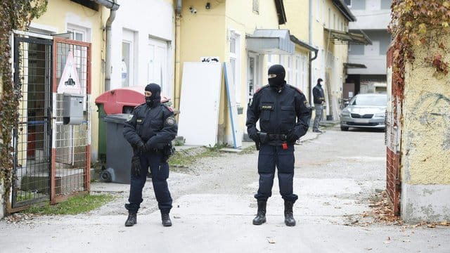 Zwei uniformierte Polizisten stehen in einer Einfahrt an einem Einsatzort der Operation "Luxor" in Graz.