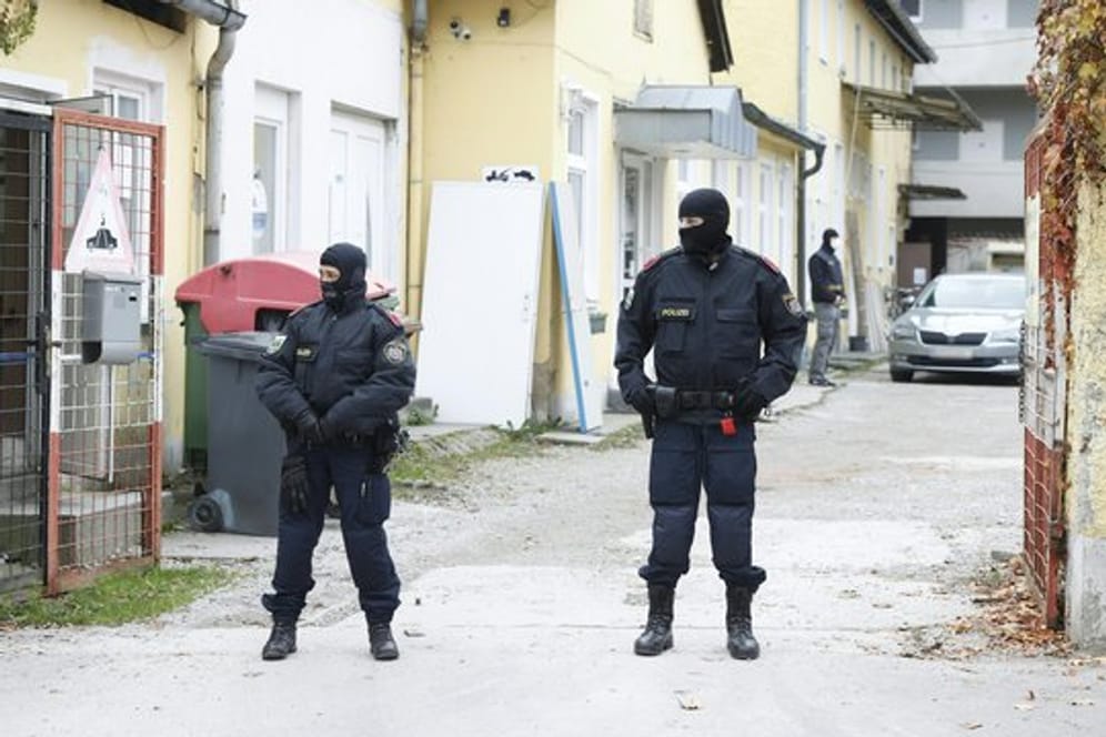 Zwei uniformierte Polizisten stehen in einer Einfahrt an einem Einsatzort der Operation "Luxor" in Graz.