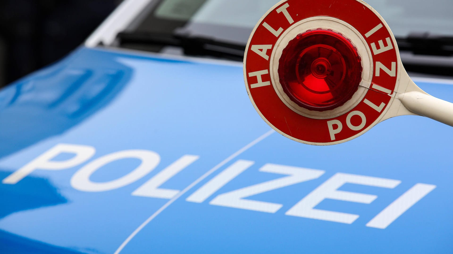 Eine Polizeikelle vor einem Einsatzfahrzeug: Beamte haben einen alkoholisierten Autofahrer gestoppt.