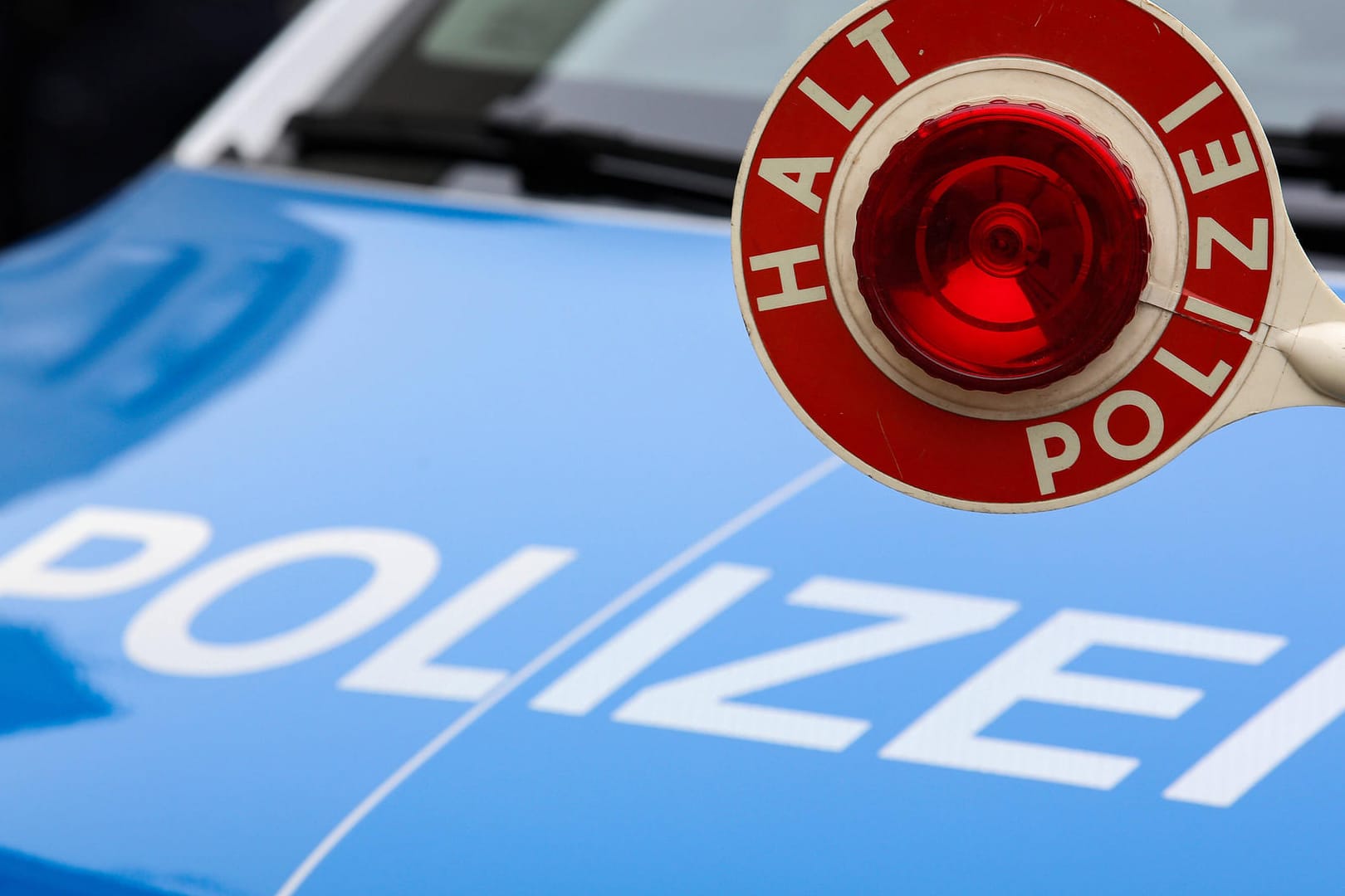 Eine Polizeikelle vor einem Einsatzfahrzeug: Beamte haben einen alkoholisierten Autofahrer gestoppt.