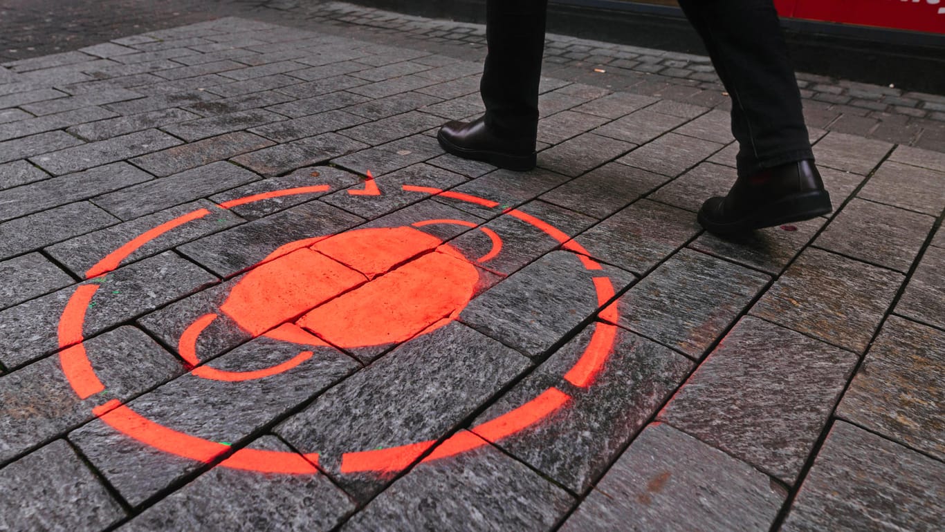 Ein Schild zur Maskenpflicht ist in Köln auf dem Boden gesprüht (Archivbild): In der Stadt ist eine Corona-Demo für den 11.11. angemeldet worden.