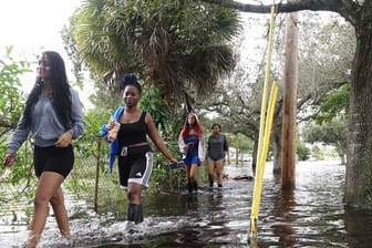 Vier junge Frauen waten durch das Hochwasser nach starken Regenfällen ausgelöst von Tropensturm "Eta" nördlich des Broward Boulevards in Florida.