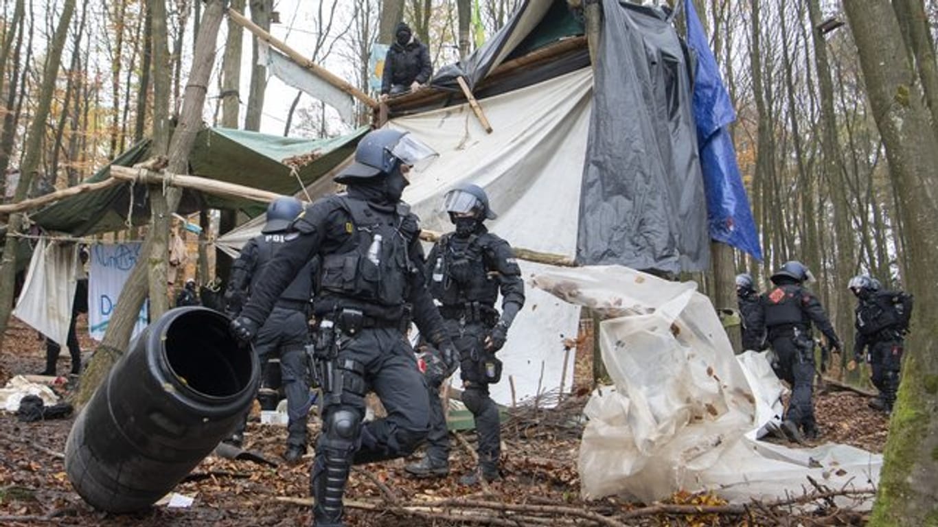 Polizisten räumen in einem Protest-Camp im Dannenröder Forst Gegenstände aus dem Weg.