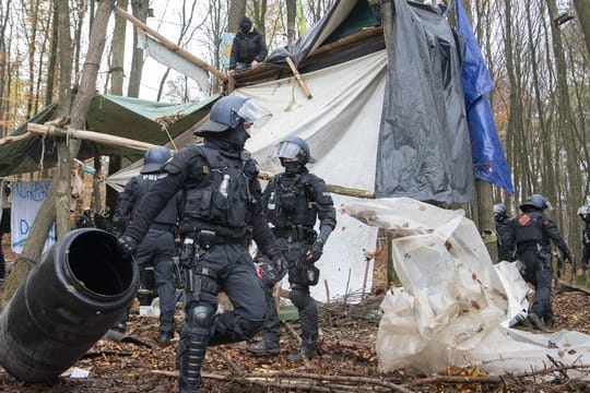 Polizisten räumen in einem Protest-Camp im Dannenröder Forst Gegenstände aus dem Weg.