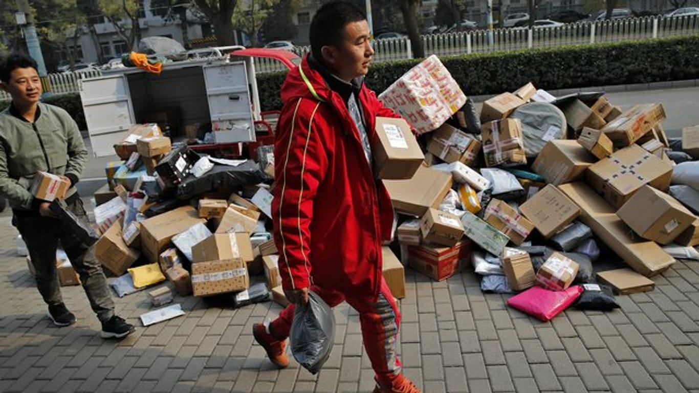 Zusteller sortieren Pakete, die sich an einem Abholpunkt in der Nähe eines Wohnhauses in Peking stapeln.