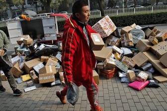 Zusteller sortieren Pakete, die sich an einem Abholpunkt in der Nähe eines Wohnhauses in Peking stapeln.