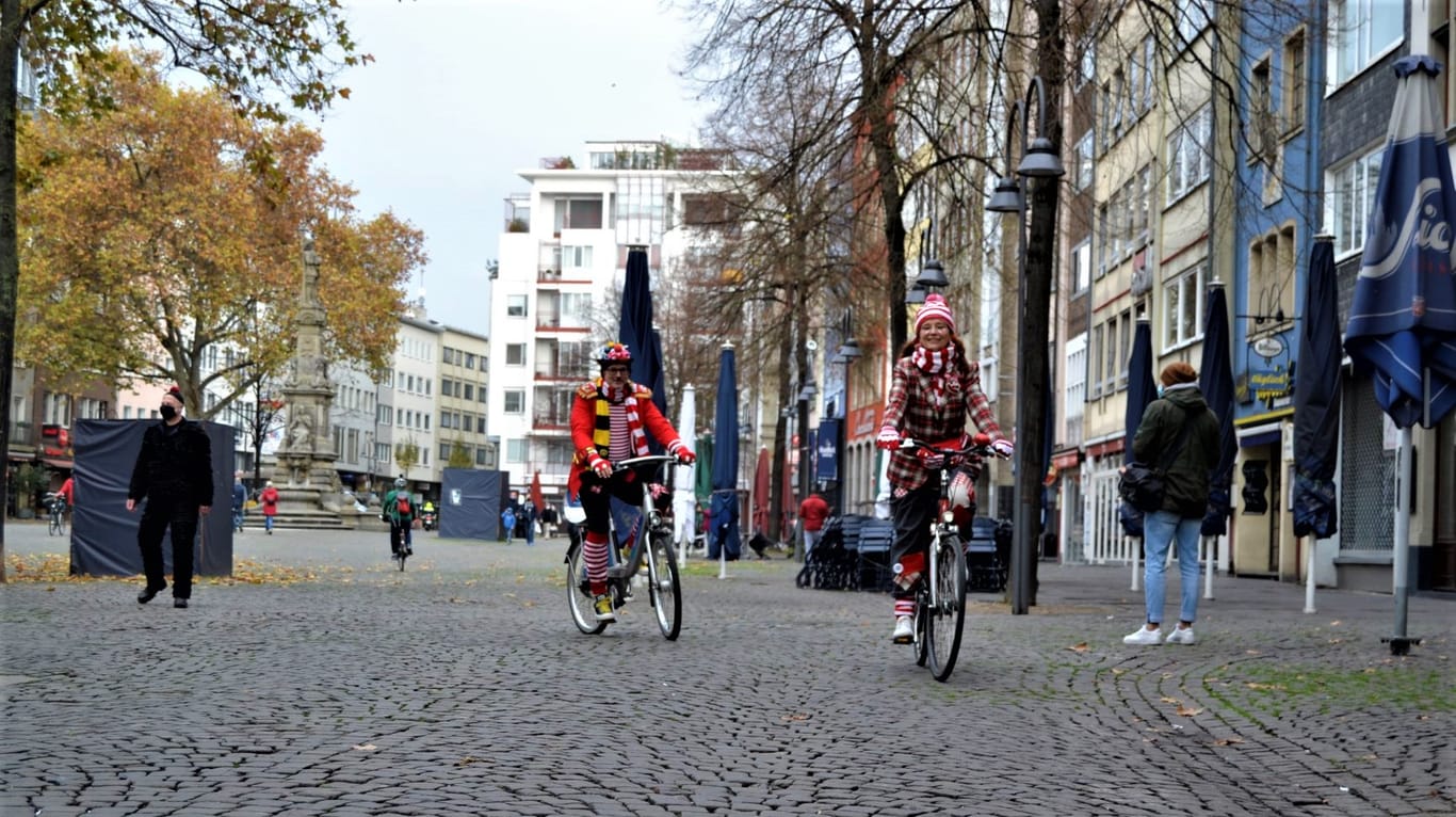 Die Kölner Ingo (li.) und Belinda (re.) fahren mit dem Rad durch die leere Altstadt in Köln: Mit "Alaaf!"-Rufen versuchen sie etwas Karnevalsstimmung am 11.11. zu verbreiten.