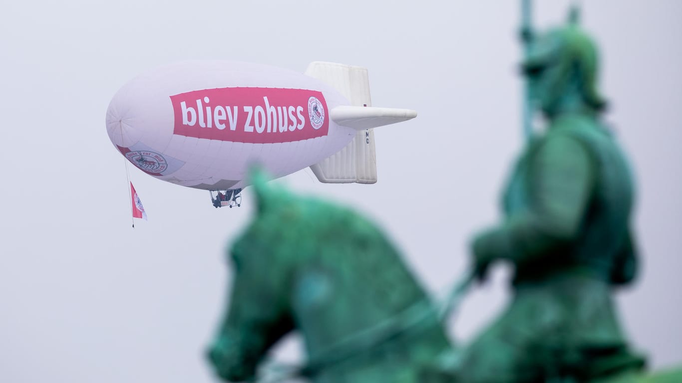 Ein Zeppelin mit der Aufschrift «bliev zohuss» (Bleib zu Hause) der Roten Funken fliegt hinter dem Reiterdenkmal am Himmel: Es flog am 11.11. über Köln und begeisterte damit die Bürger.