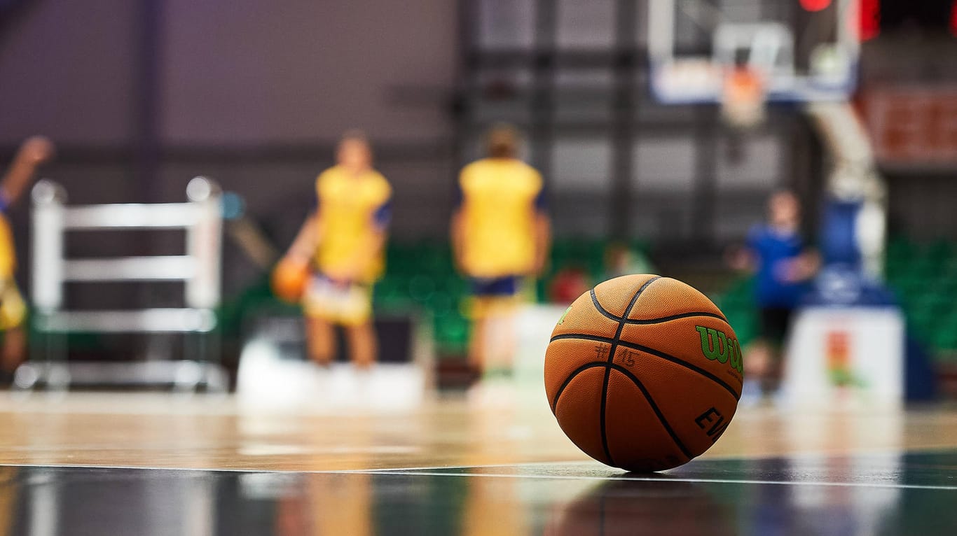 Ein Basketball liegt in einer Halle auf dem Boden (Symbolbild): Nachdem bei Phoenix Hagen mehrere Spieler und das Trainerteam positiv auf Corona getestet worden sind, müssen einige Spiele abgesagt werden.