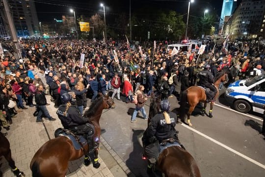 Teilnehmer der Demonstration stehen am Leipziger Hauptbahnhof vor der Reiterstaffel der Polizei.