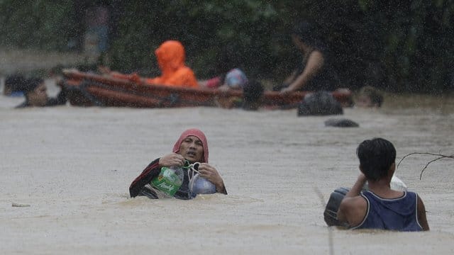 Ein Mann in Marikina benutzt Plastikbehälter, um sich beim Überqueren einer überfluteten Straße über Wasser zu halten. Ein Mann in Marikina benutzt Plastikbehälter, um sich beim Überqueren einer überfluteten Straße über Wasser zu halten.