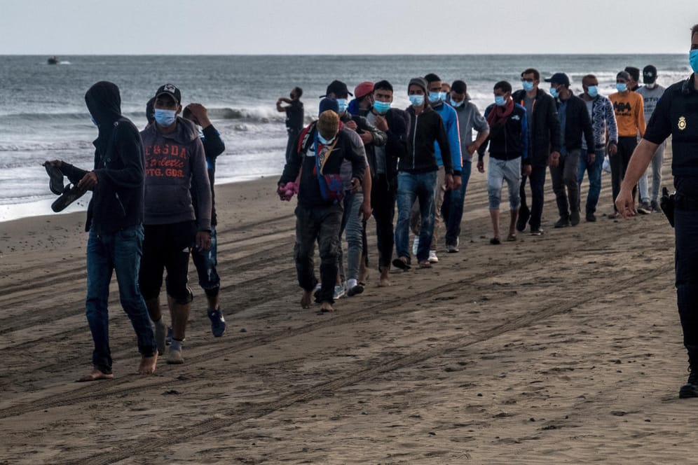 Migranten aus Marokko und ein spanischer Polizist auf Gran Canaria: Seit Jahresbeginn erreichten knapp 14.000 Migranten die Inselgruppe vor Westafrika.
