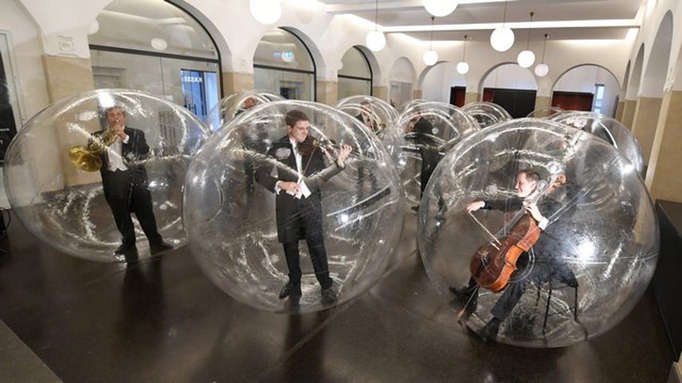 Musiker stehen und sitzen in transparenten Bällen: Musiker der Stuttgarter Philharmoniker spielen während der Kunstaktion "Social Distance Stacks".