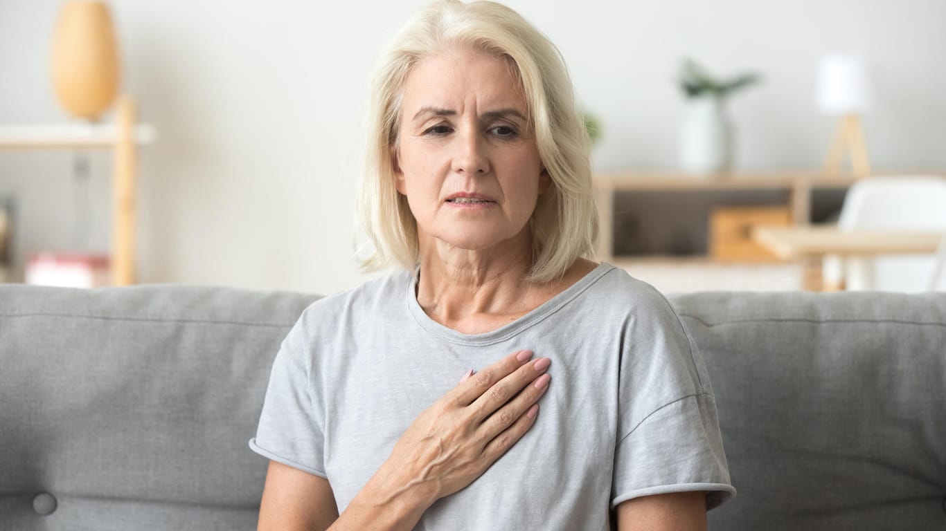Eine Frau fasst sich an die Brust: Frauen sterben in Deutschland seltener als Männer in Folge eines Herzinfarkts.