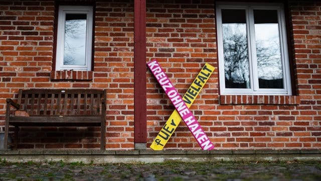 Ein Holzkreuz mit der Aufschrift "Kreuz ohne Haken - fuer Vielfalt" steht an einer Hauswand in Haarstorf im Kreis Uelzen. Ein Holzkreuz mit der Aufschrift "Kreuz ohne Haken - fuer Vielfalt" steht an einer Hauswand in Haarstorf im Kreis Uelzen.