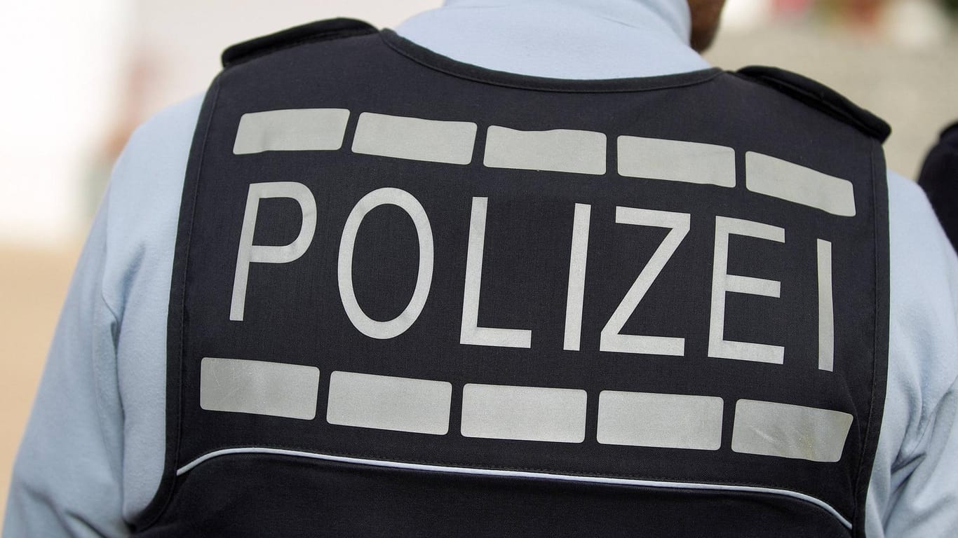 Ein Mann in Polizeiuniform von hinten (Symbolbild): In Bonn hat die Polizei zwei Männer festgenommen, die sich fälschlicherweise als Polizisten ausgegeben hatten.