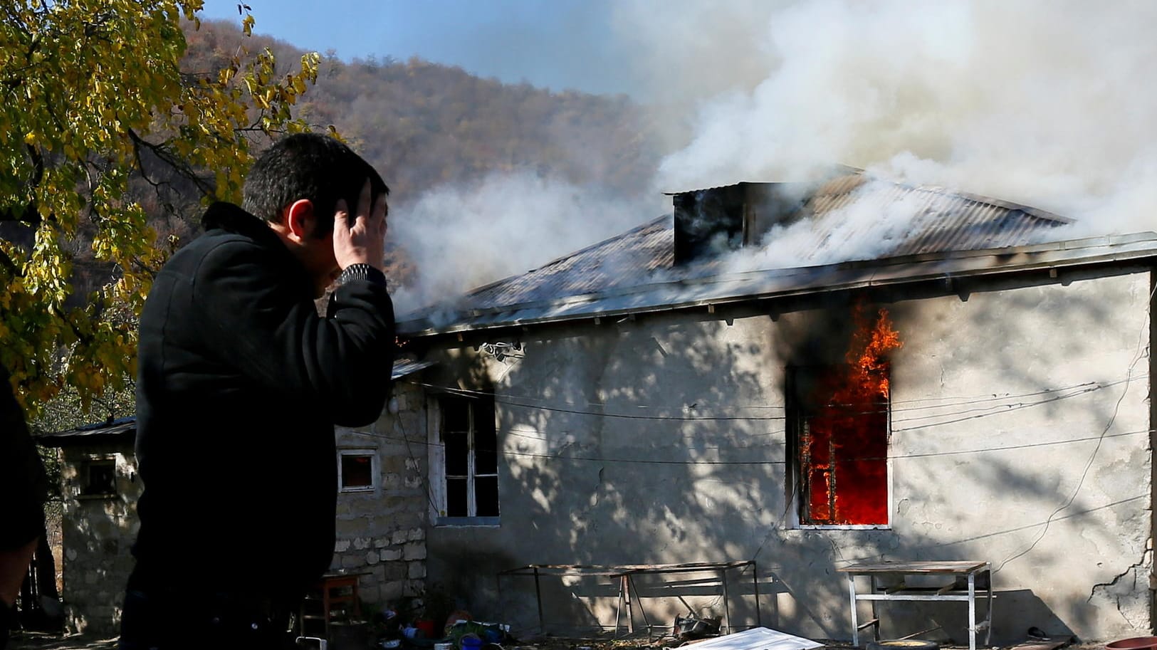 Ein Mann vor einem brennenden Haus: Armenier flüchten aus dem Gebiet, was nach dem Abkommen Aserbaidschan zugesprochen wurde.