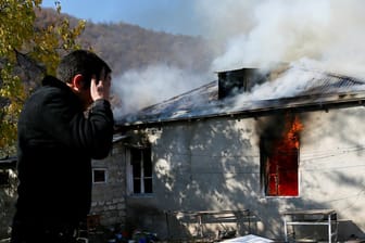 Ein Mann vor einem brennenden Haus: Armenier flüchten aus dem Gebiet, was nach dem Abkommen Aserbaidschan zugesprochen wurde.