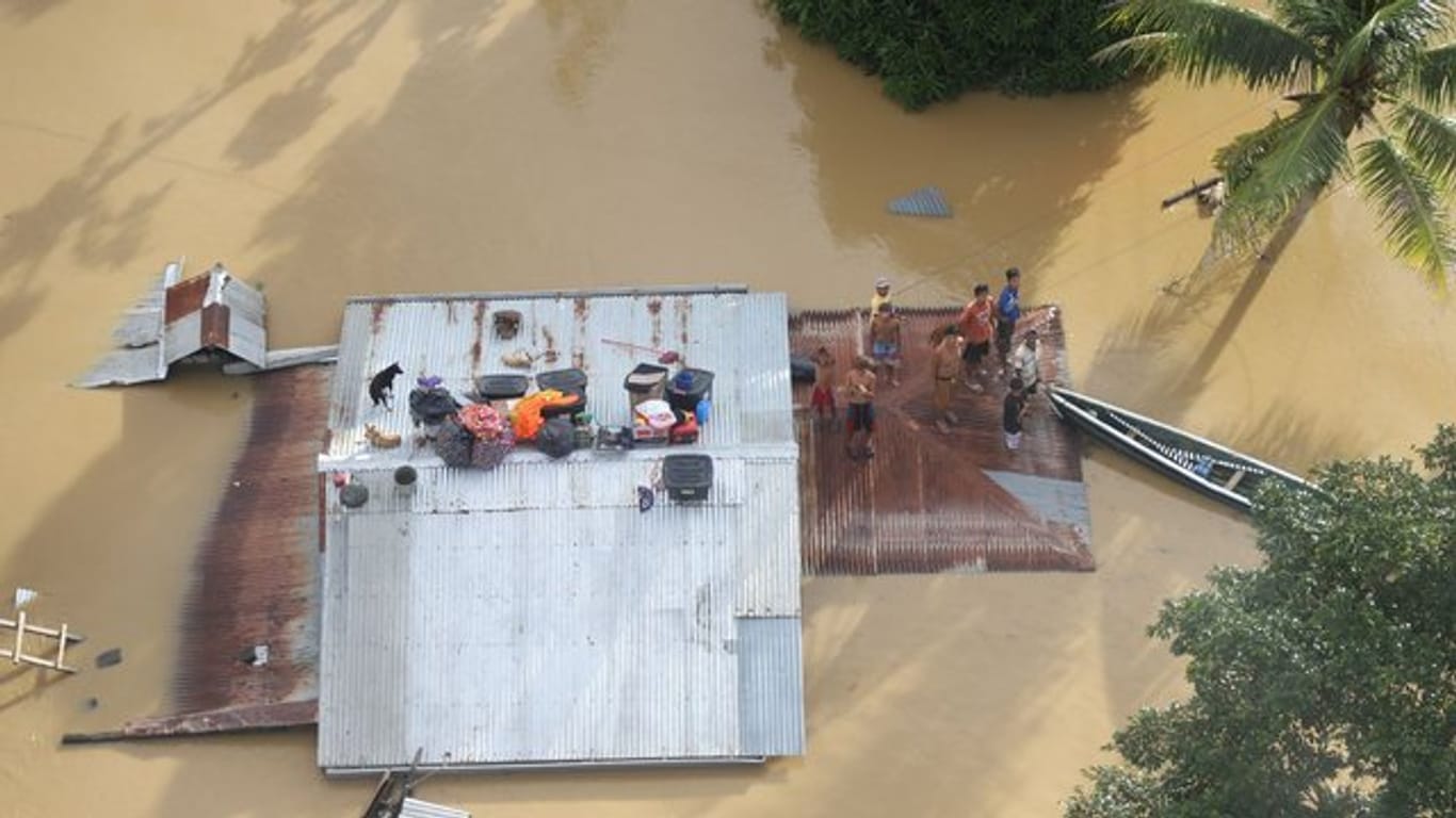 Menschen stehen auf dem Dach eines überfluteten Hauses bei Cagayan auf den Philippinen.