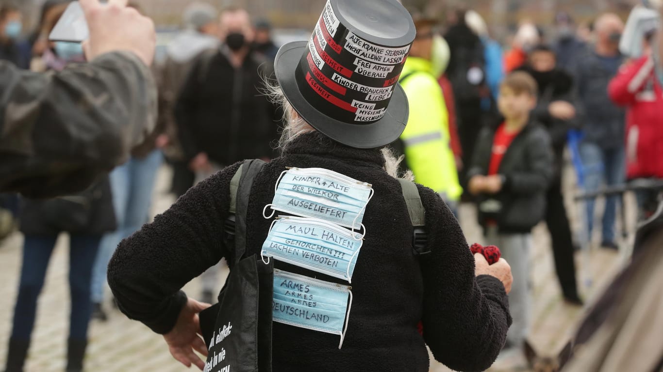 Mund-Nase-Masken mit Slogans gegen die Corona-Maßnahmen sind auf der Jacke einer Frau befestigt, die an einer Demonstration der Initiative «Querdenken 211» teilnimmt: Zu der Kundgebung kamen weniger Menschen als erwartet.